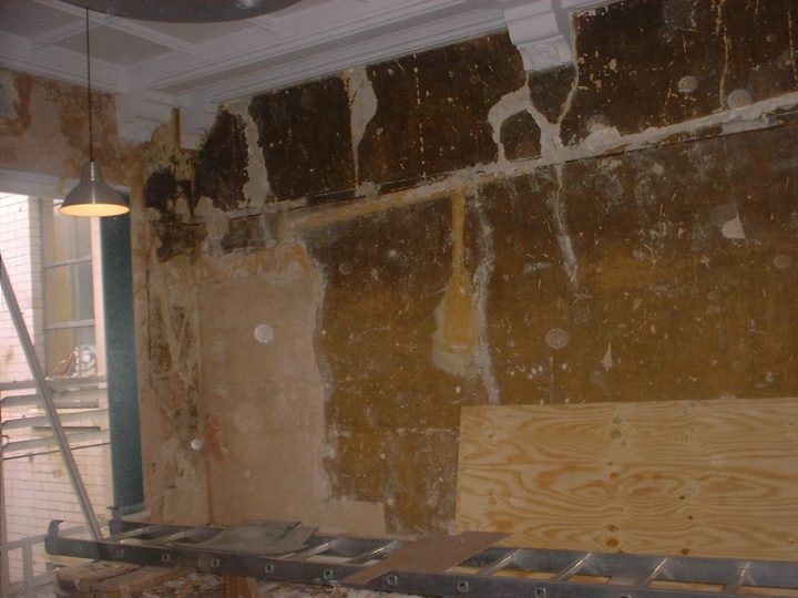 Layers of old wall finishes revealed beneath a moulded cornice